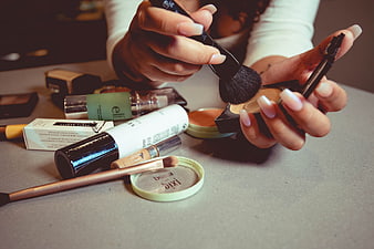 Woman applying makeup with brushes and cosmetics on table