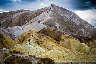 Hikers climbing colorful volcanic mountain landscape