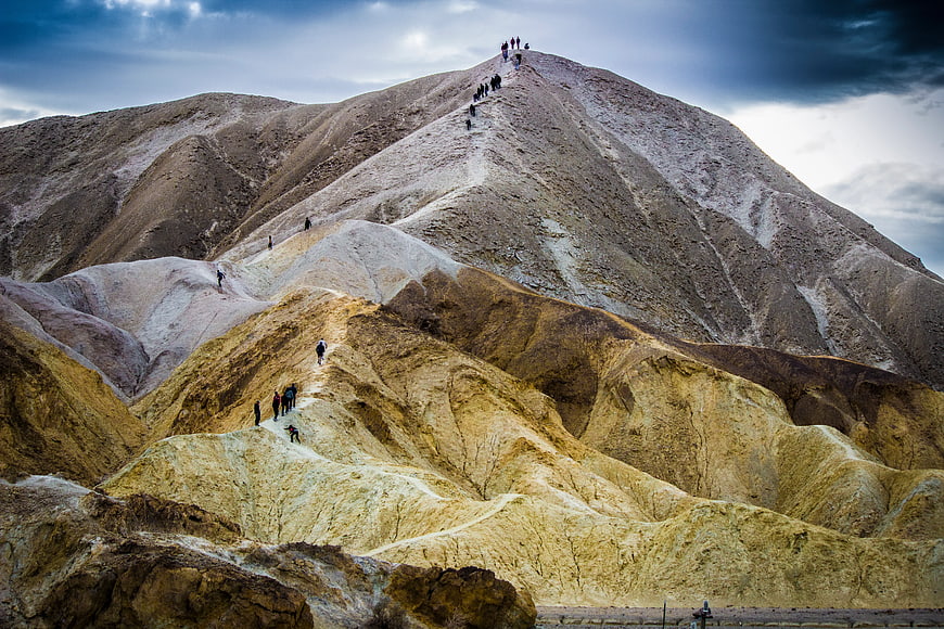 Hikers climbing colorful volcanic mountain landscape