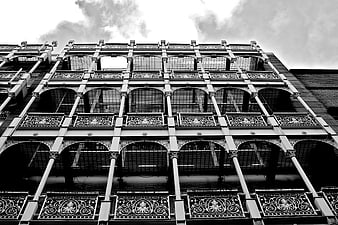 Low-angle black and white view of ornate ironwork building facade
