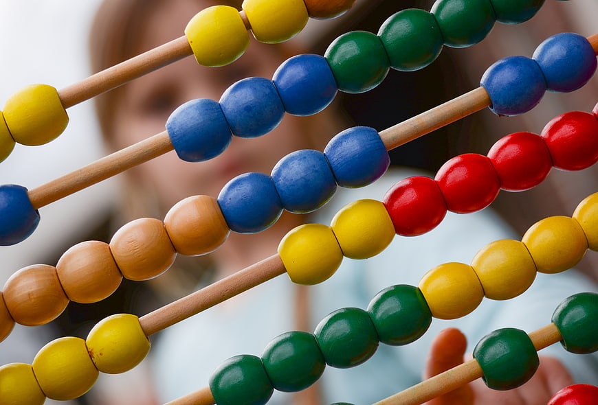 Close-up of colorful wooden abacus beads with blurred child background