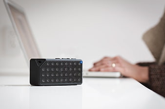 Black Bluetooth Speaker on White Desk with Laptop