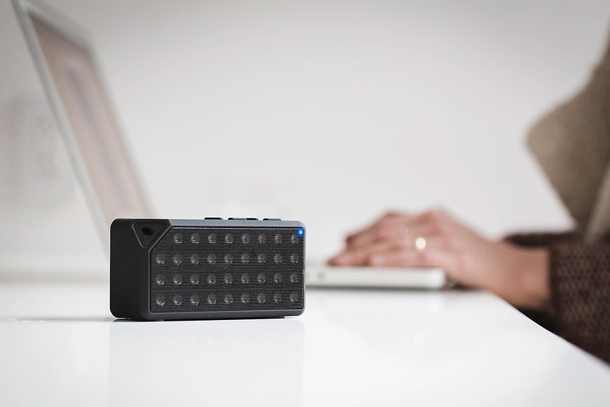 Black Bluetooth Speaker on White Desk with Laptop