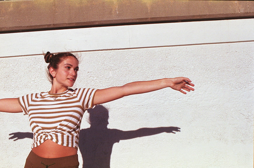 Young woman in striped crop top posing against white wall