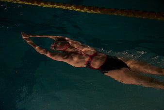 Woman swimming freestyle in a dark indoor pool