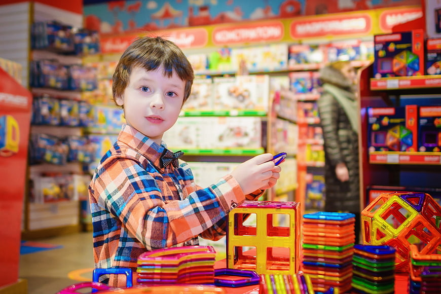 Young boy playing with magnetic building blocks in toy store