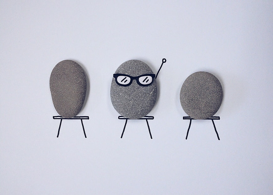 Creative stones with drawn glasses and chairs on white background