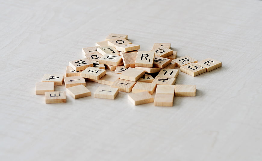 Scattered wooden Scrabble tiles on white background
