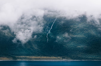 Misty Mountain Waterfall Overlooking a Serene Blue Lake