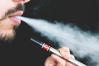Close-up of man exhaling vapor from electronic cigarette