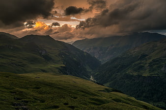 Dramatic mountain landscape with golden sunset light breaking through dark clouds