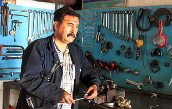 Middle-aged mechanic working in workshop with tools
