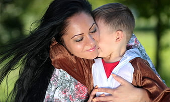Mother holding son in bear costume outdoors