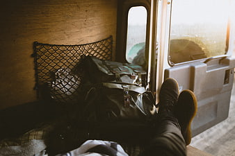 Relaxed traveler resting in van with bags and boots
