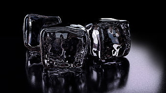 Three glossy black ice cubes on a reflective dark surface