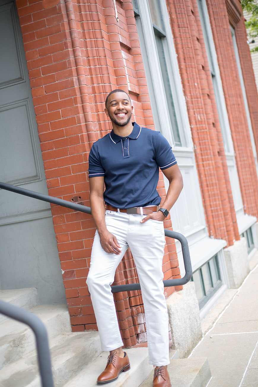 Confident young black man in navy polo and white pants