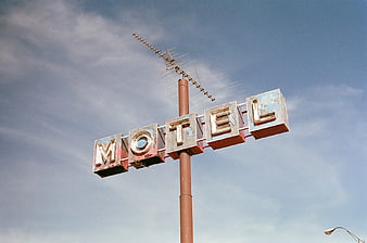 Vintage Rusty Motel Sign Against Blue Sky