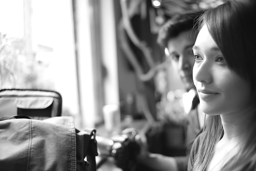 Black and white portrait of woman smiling with man in background