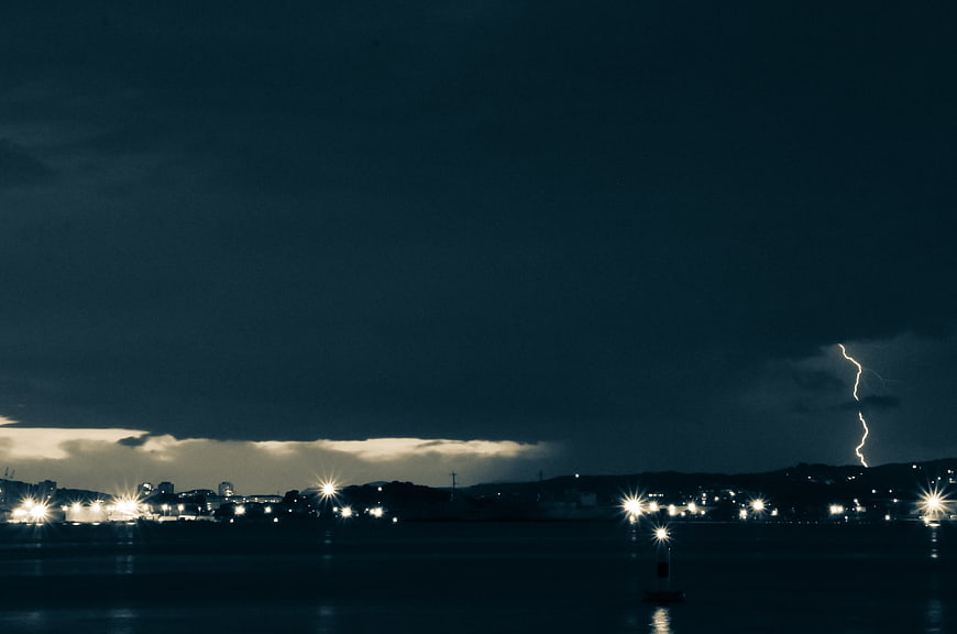 Dramatic Lightning Strike Over Coastal City at Night
