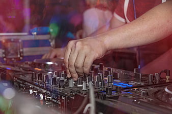 DJ Hand Adjusting Mixer Knobs In Dark Club