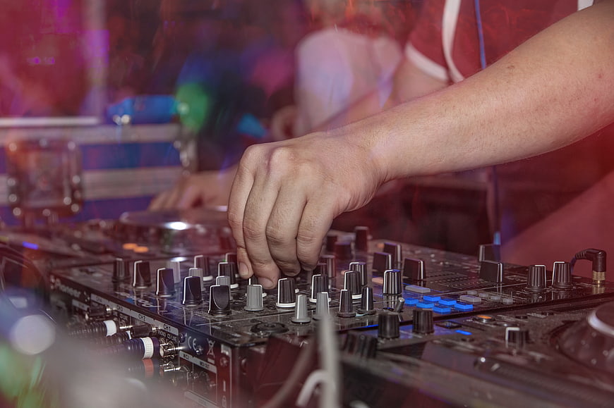 DJ Hand Adjusting Mixer Knobs In Dark Club