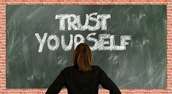 Woman looking at chalkboard with trust yourself written