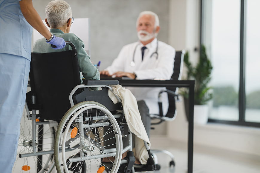 Doctor consulting elderly patient in wheelchair