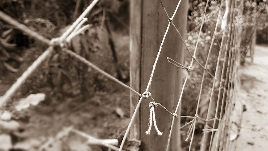 Close-up of rustic rope net tied to wooden post