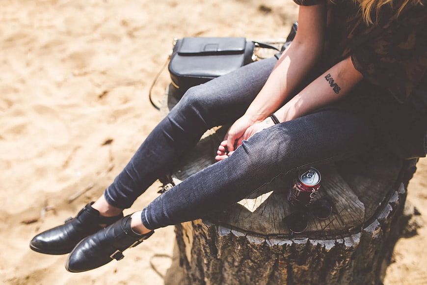 Woman in Jeans and Boots Sitting on Tree Stump