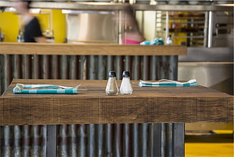 Empty wooden restaurant table with cutlery and condiments
