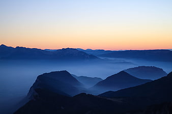 Misty mountain landscape at dawn with blue hour fog