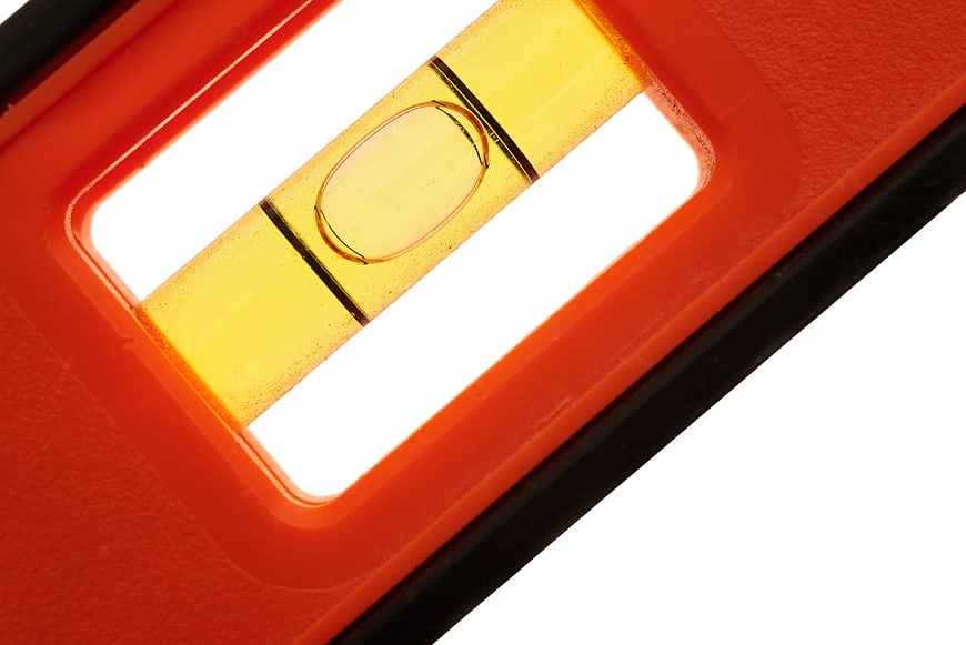 Close-up of orange spirit level bubble on white background