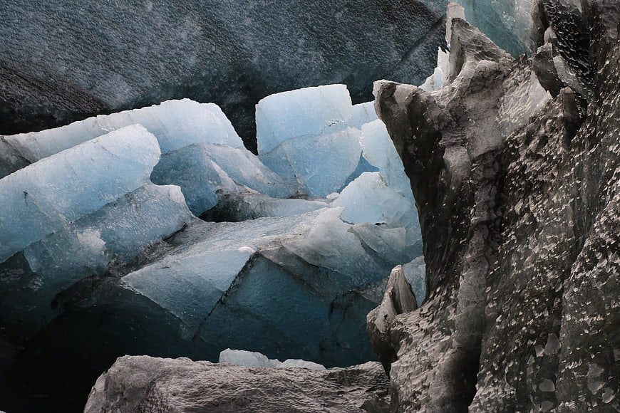 Close-up of jagged blue glacier ice with dark rocky textures