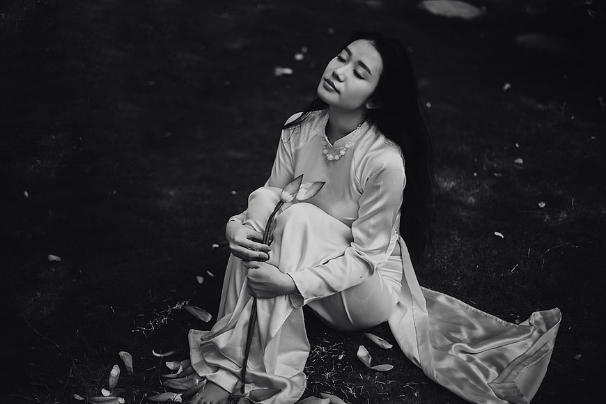 Elegant woman in traditional dress sitting with lotus flower