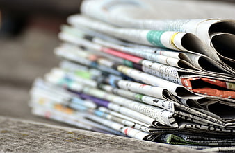 Stack of folded newspapers on a rustic wooden table
