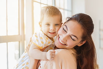 Happy Mother Hugging Smiling Toddler Son Indoors