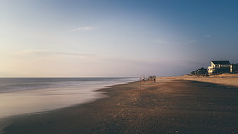 Serene Beach Landscape with Houses and Blurred Figures