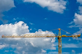 Yellow Tower Crane Against Blue Sky with Clouds