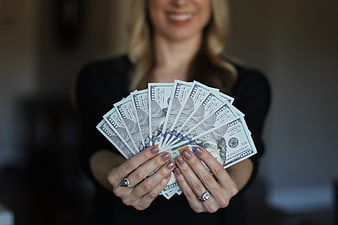 Woman holding fan of hundred dollar bills