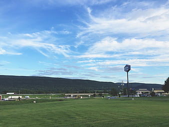 Wide rural landscape with highway, mountains, and blue sky