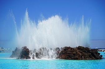 Dramatic Geysers Erupting from Volcanic Rocks in Turquoise Water