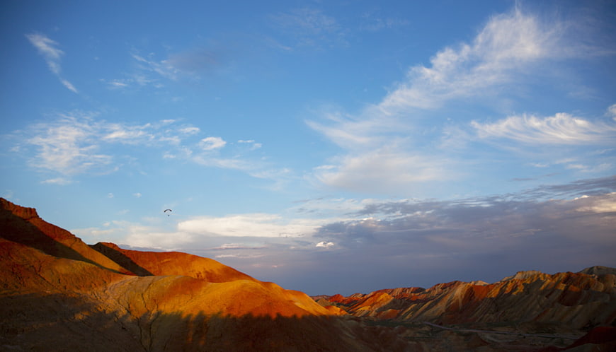 Colorful Danxia Landscapes Under Blue Sky with Paraglider