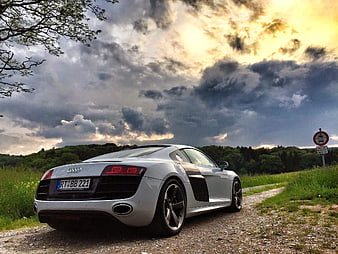 Silver Audi R8 Sports Car Parked On Gravel Road Under Dramatic Sky