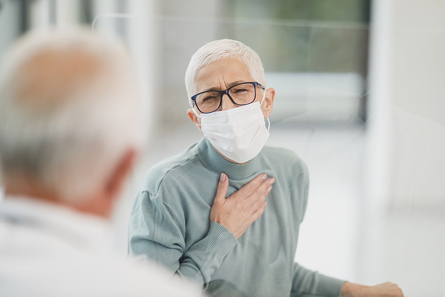 Senior woman with chest pain wearing medical mask