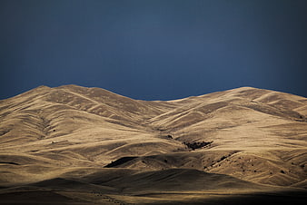 Golden rolling hills under deep blue sky landscape