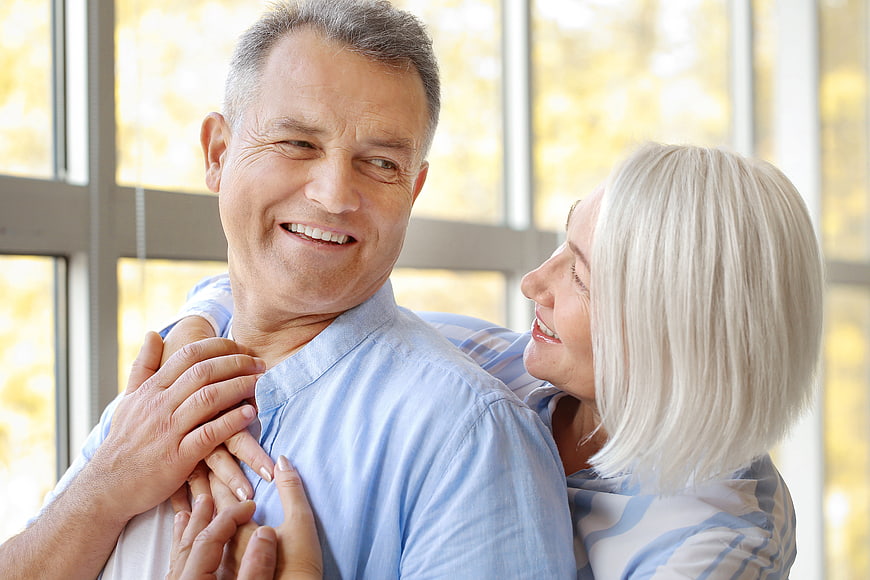 Happy senior couple embracing indoors with natural light
