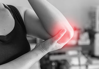 Woman holding elbow with red pain indicator in gym