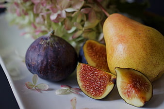 Fresh Figs and Pear on White Plate with Flowers