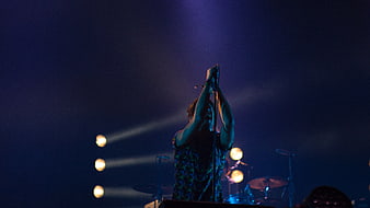 Male singer performing on stage with dramatic blue lighting