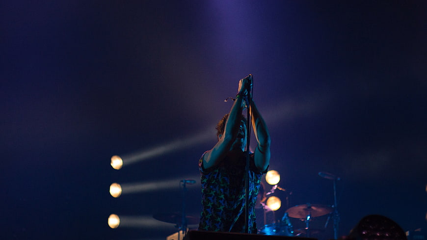 Male singer performing on stage with dramatic blue lighting